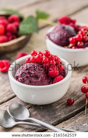 Delicious and romantic dessert. A ball of homemade raspberry walrus with fresh berries  in a white cup on a wooden  background. Close up