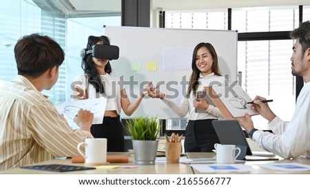 Diverse young businesspeople brainstorming together in the office and using virtual reality headset