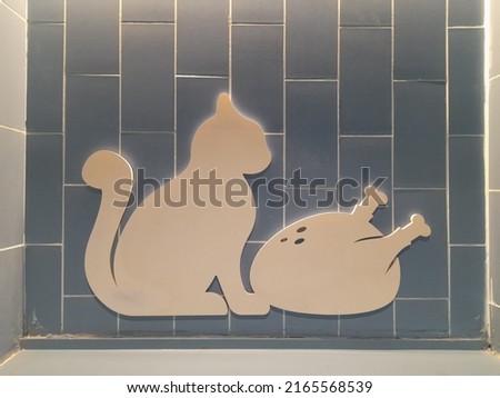 icon cutout beige image on blue tiled wall of cat with roasted chicken 