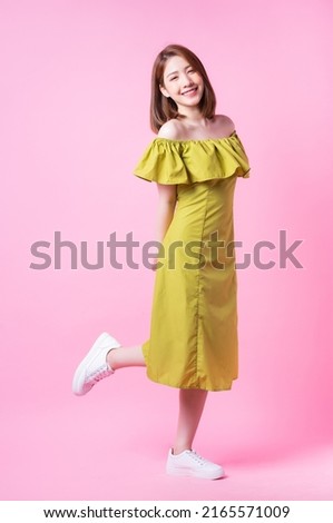 Image of young Asian woman wearing green dress on pink background Royalty-Free Stock Photo #2165571009
