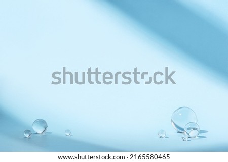 Blue background with transparent glass balls. Minimal concept and hard sunlight.