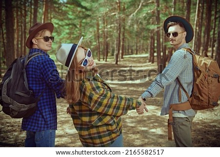 Happy young people hipsters tourists go for a walk in a pine forest. Thirst for adventure, hiking. Summer vacation. Denim style.