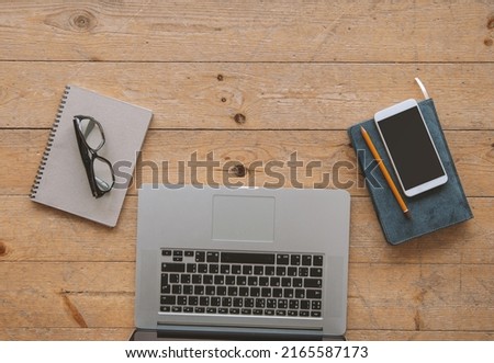 Laptop, paper notebook, smartphone and eyeglasses on the wooden floor. Mock up for design