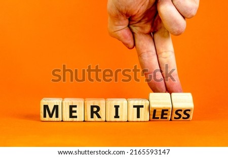 Merit or meritless symbol. Businessman turns wooden cubes and changes the word meritless to merit. Beautiful orange table, orange background. Business and merit or meritless concept. Copy space.