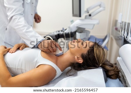 Doctor making ultrasound of thyroid gland to woman patient in clinic. Diagnosis and treatment of autoimmune thyroiditis concept Royalty-Free Stock Photo #2165596457