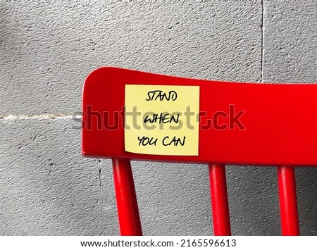 Red chair with stick note written STAND WHEN YOU CAN, to remind oneself to sit less , combat sedentary lifestyle, be being active and move more Royalty-Free Stock Photo #2165596613