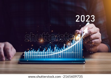 Businessman planning 2023 business growth on desk with virtual hologram chart graph. Calculate income and profit on investments and an increase in the indicators of positive growth Royalty-Free Stock Photo #2165609735