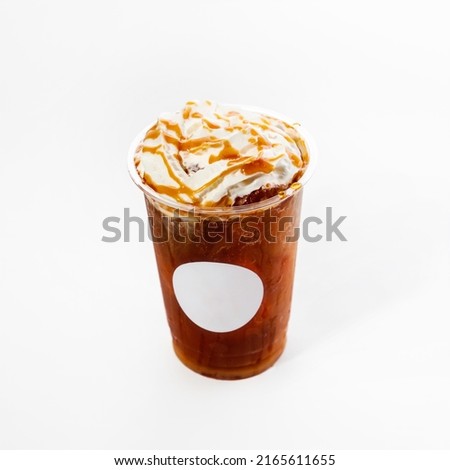 Plastic glass with cold coffee frappe with ice cubes on a white background, decorated with whipped cream and caramel, close-up. Mock up.