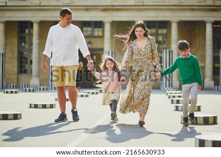 Happy family of four enjoying their trip to Paris, France. Mother, father, son and daughter in Palais Royal garden in Paris. Married couple with kids travelling in France