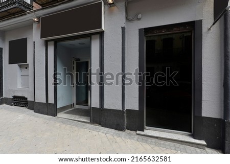 Local facade with gray stone walls, black details and black signs