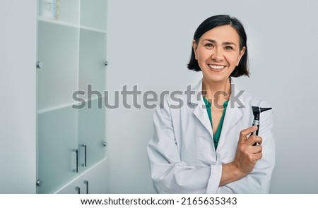 Woman audiologist with otoscope standing in medical clinic. Ear treatment and hear exam Royalty-Free Stock Photo #2165635343