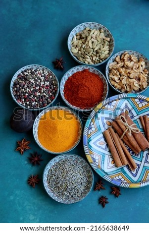 Top view arrangement with spices in bowls. Colorful picture of aromatic Indian herbs and spices on a table. Blue background with copy space. 