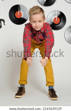 Retro disco 60s, 70s, 80s concept, funny boy wearing checked shirt and stylish haircut on a background with music plate