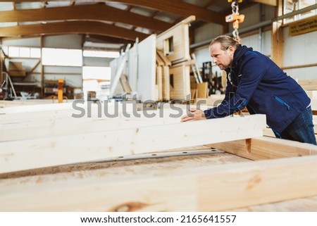Carpenter working on a wooden wall. Prefabricated house Royalty-Free Stock Photo #2165641557