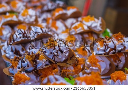 Close-up picture of thai crispy pancake, Thai name “Khan Bueng”, topped with whipped cream and shredded egg yolk. It is a street snack and is a popular dessert in various festivals.
