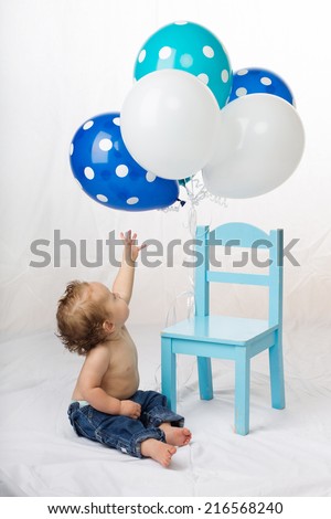 Reaching for balloons Baby boy sitting on floor reaching for balloons on his first birthday