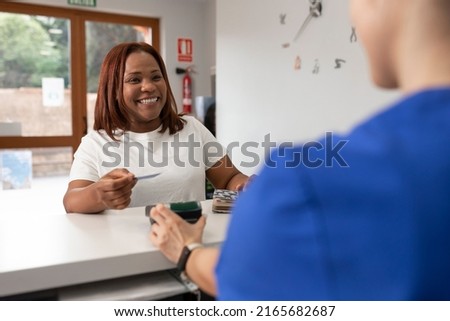A black woman smiles with joy holding her credit card before paying in return for the good service she has received at the dental clinic Royalty-Free Stock Photo #2165682687