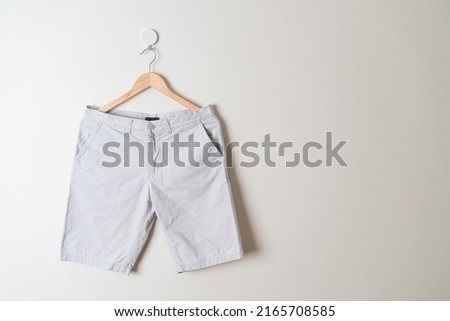 short pants hanging with wood hanger on wall Royalty-Free Stock Photo #2165708585