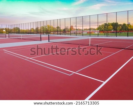 New outdoor red tennis courts with white lines and gray pickleball lines.	 Royalty-Free Stock Photo #2165713305