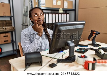 African woman working at small business ecommerce with hand on chin thinking about question, pensive expression. smiling with thoughtful face. doubt concept. 