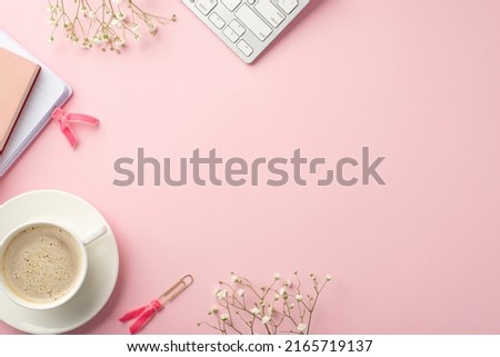 Business concept. Top view photo of keyboard diaries cup of frothy coffee on saucer clips and white gypsophila flowers on isolated pastel pink background with copyspace