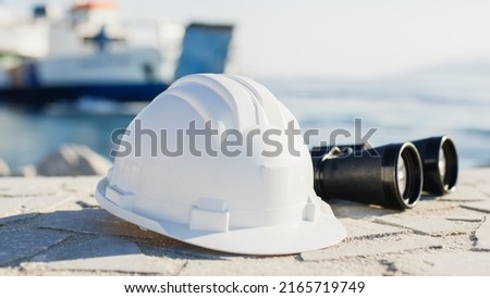 White engineer helmet and binoculars in a naval port Royalty-Free Stock Photo #2165719749