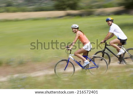 Couple riding bicycles on rural path