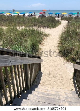 A staircase leads beach goers down to a path to the beach. Atlantic Ocean in the background.