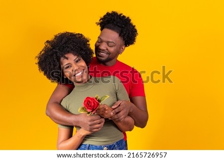 black couple hugging on yellow background and woman holding a flower bud