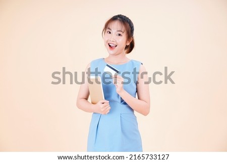 Portrait of Asian young beautiful and cheerful woman using credit card to pay online, isolated on background