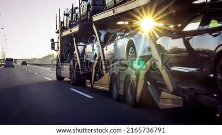 Car transporter trailer loaded with many cars on a highway, motion blur effect. Royalty-Free Stock Photo #2165736791