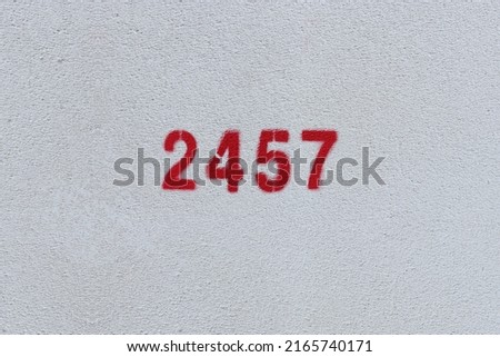 Red Number 2457 on the white wall. Spray paint.
