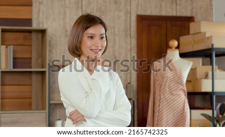 Young woman Asian Tailor Shop Owner, Close-up of the face of female mechanic who poses with her arms crossed behind her desk, Small business Professional Design clothes to sell online.