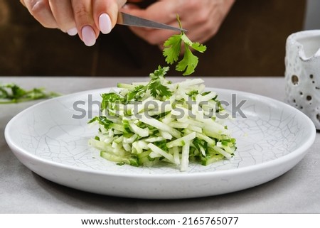 Radish daikon and sliced cucumber in a plate. Tasty and healthy food. Cooking and home recipes. Shallow depth of field