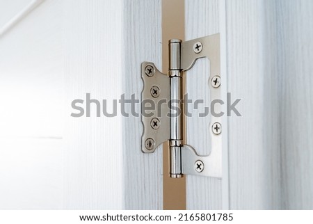 Door hinges cut into the wooden door, chrome interior details, connecting fastening screwed on screws, construction part. High quality photo Royalty-Free Stock Photo #2165801785