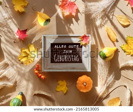 Text Alles Gute zum Geburtstag in German means Happy Birthday. Dry Fall leaves on beige cardboard background with sunlight, long shadows.