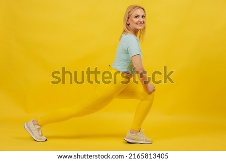 portrait of a smiling mature woman doing stretching exercises on a yellow background. The concept of a healthy lifestyle