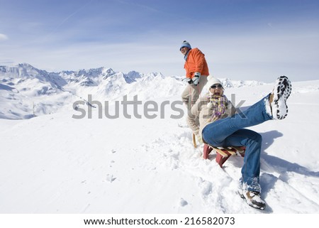 Man puling wife through snow on sled