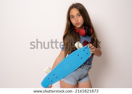Young brunette girl isolated on white background standing with a skateboard.
