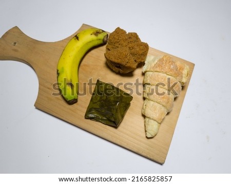 Market snacks on wooden trays are mendut cake, cum cum cake, blooming chocolate sponge, and banana