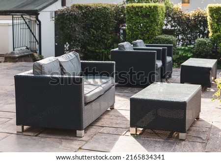 Brown rattan patio furniture with grey upholstery arranged on a patio area