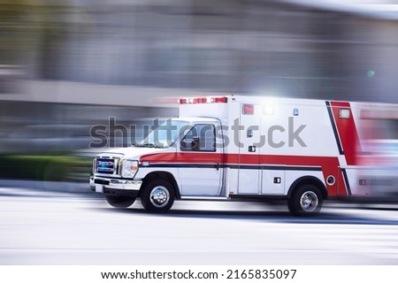 Blurred motion action view of an ambulance responding to the scene of an emergency. Royalty-Free Stock Photo #2165835097
