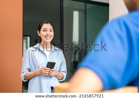 Young woman signing electronic Signature on smartphone for agreement of contract digital receiving parcel from blue delivery man from shopping online. Courier man delivering package to destination.