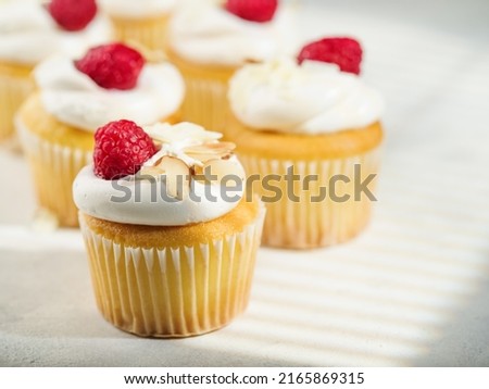 Close-up. Muffins with whipped cream, raspberries and almonds. Isolated on white background. There are no people in the photo. Sweet food, calories. Banquet, picnic, holiday, birthday.