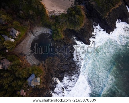 Shooting from a drone. An ocean with waves crashing against a sandy hilly shore and a pine forest on the shore. Abstraction. There are no people in the photo. Calm scenes, ecology, tourism.