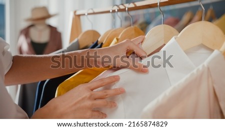 Close-up hand Cheerful young Asia lady shopping new outfit for gift  choose cloth and dress in mall shop or cloth store. Shopaholic girl, special offer price, holiday activity lifestyle concept. Royalty-Free Stock Photo #2165874829