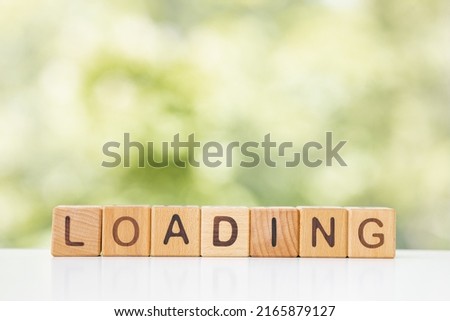 Loading Word In Wooden Cubes on green summer background