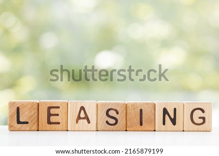LEASING word is made of wooden blocks lying on the table, concept, green summer background