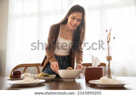 Woman place the curry cup, set the food on the table. Royalty-Free Stock Photo #2165890205