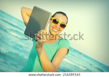 Girl photographs selfie on the beach at sunset